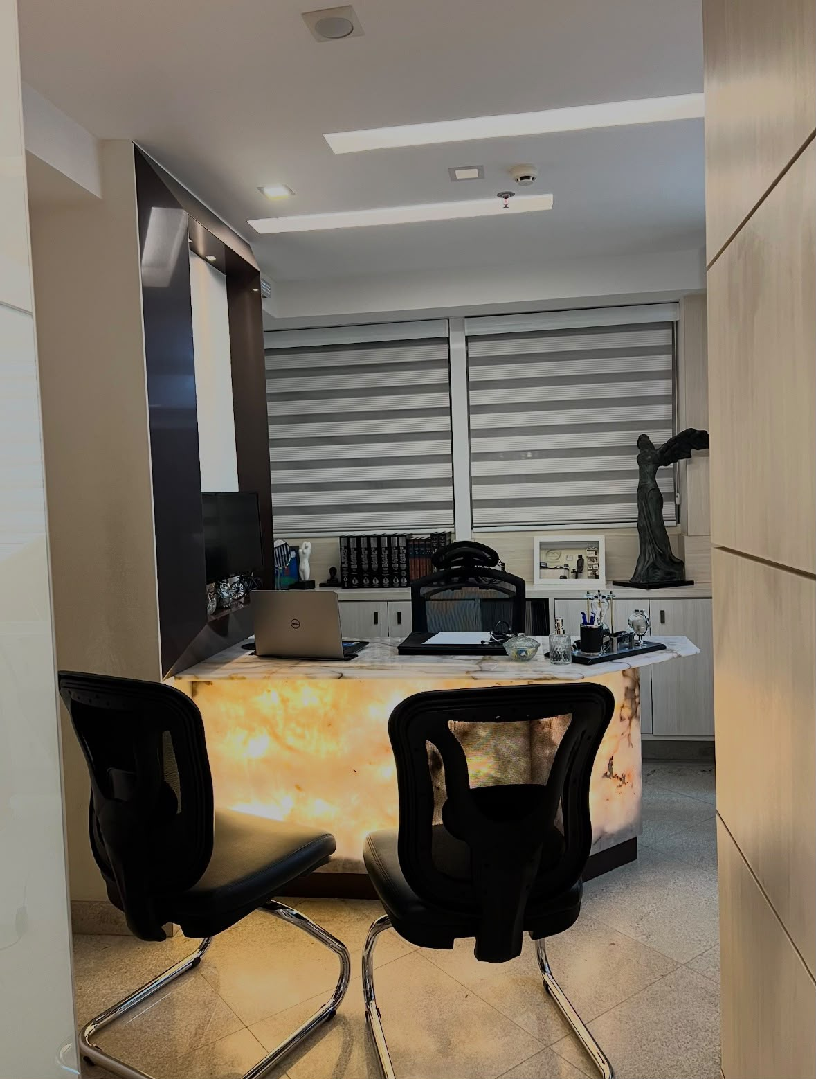 Consultório médico com mesa de atendimento e cadeiras.